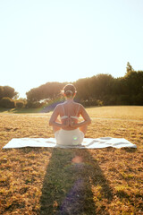 Young woman in sportswear stretching body on fitness mat at public park, doing yoga. Healthy...