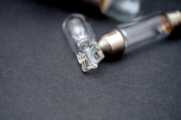 Glass tube light bulbs lying on a dark surface with one bulb damaged showing intricate inner components