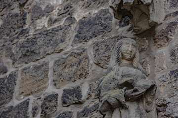 Detailed old stone sculpture of female figure with long hair on Gothic church facade in Germany