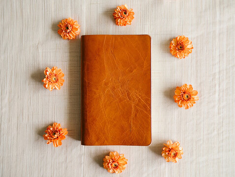 Orange flowers surrounding leather journal notebook