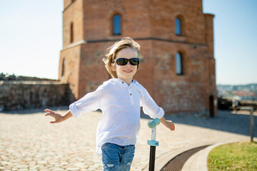 Smiling child poses with outstretched arms in front of the iconic Gediminas Tower in Vilnius,...