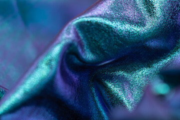 Close-up of shimmering iridescent metallic fabric in blue and violet tones, abstract luxury textile background for fashion, design, futuristic style and creativity