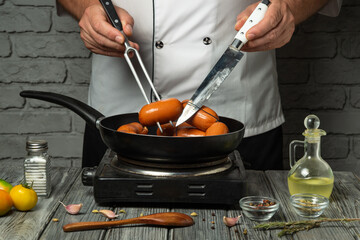 A chef skillfully flips sausages in a skillet over a stove. Fresh vegetables and spices surround...
