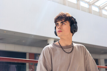 Sad teenage boy wearing headphones, looking away with serious expression. Concept of depression, loneliness, mental health issues, heartbreak, anxiety, stress, teenage problems. Copyspace © Светлана Мищенко