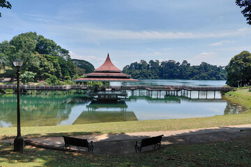 Tranquil lakeside scene with gazebo and verdant trees under clear blue sky