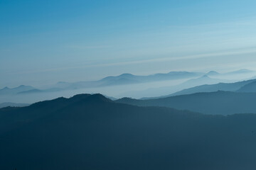 Dramatic aerial view of mountains surrounded by thick cloud beds.