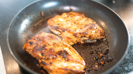 Seasoned chicken fillet sizzling in a frying pan, cooked to a golden brown with herbs and spices. Perfect for healthy eating content, quick dinner ideas, or home cooking blogs. Close-up shot with stea