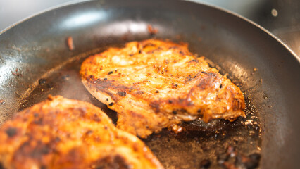 Seasoned chicken fillet sizzling in a frying pan, cooked to a golden brown with herbs and spices. Perfect for healthy eating content, quick dinner ideas, or home cooking blogs. Close-up shot with stea