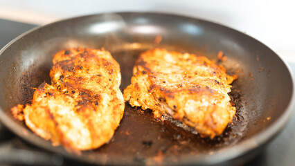 Seasoned chicken fillet sizzling in a frying pan, cooked to a golden brown with herbs and spices. Perfect for healthy eating content, quick dinner ideas, or home cooking blogs. Close-up shot with stea