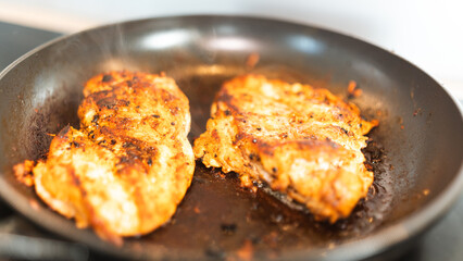 Seasoned chicken fillet sizzling in a frying pan, cooked to a golden brown with herbs and spices. Perfect for healthy eating content, quick dinner ideas, or home cooking blogs. Close-up shot with stea