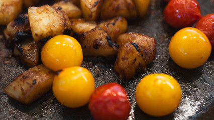 Sizzling colorful tomatoes and cassava slices frying in a pan as a side dish. Perfect for rustic cuisine, home cooking tutorials, or comfort food content. Close-up shot with dynamic action and steam.