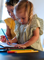Mother and daughter enjoy drawing together indoors