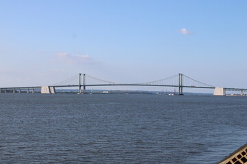 View of a Modern Suspension Bridge Spanning Across a Calm Body of Water Under a Clear Sky, Showcasing Engineering Marvel Against a Peaceful Landscape