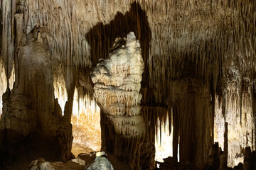 Mysterious cave formations with stalactites and stalagmites illuminated by soft light