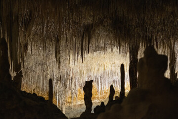 Dramatic stalactites and stalagmites in a dimly lit underground cave