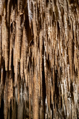 Obraz premium Stalactites in remarkable cave: natural mineral formations and textures captured in rugged earth colors