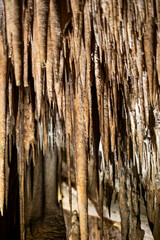 Majestic brown stalactites in a dimly lit cave interior