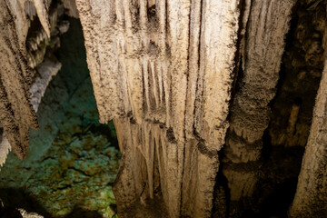Majestic stalactites inside mysterious cave with reflective water pool