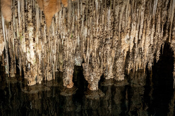 Stalactites reflecting in underground water inside majestic cave interior