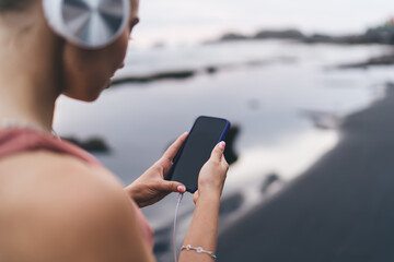 Tech-focused woman in terracotta activewear taps smartphone with concentration, embodying the fusion of digital rhythm, physical stillness and guided internal experience.