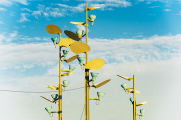 Unique yellow streetlights and reflectors arranged as a modern art piece against the sky.