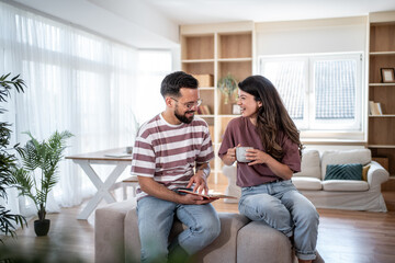 Happy couple relaxing at home, browsing tablet and enjoying coffee