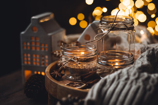 Cozy home holiday atmosphere. Idea for handmade christmas decorations: aromatic candles in glass jars. Cinnamon sticks, anise, dry citrus, homemade gingerbread cookies. Fairy lights