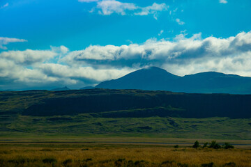Fototapeta premium Majestic Icelandic Mountains with Cloudy Sky and Green Fields