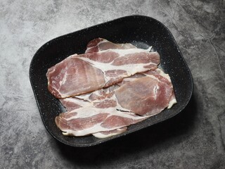 Raw smoked back bacon rashers on a non stick roasting tray.