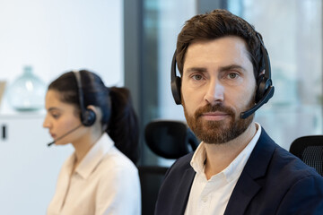 Professional male call center agent wearing a headset in a modern office