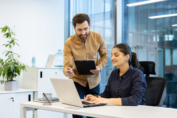 Friendly office conversation between a manager and employee in a modern workspace