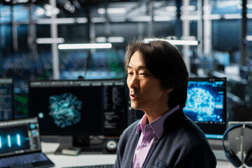 Programmer in data center optimizing infrastructure for AI tasks, increasing workloads. Asian...