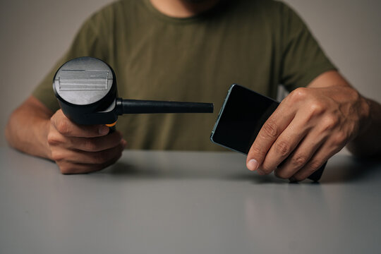 Close-up of technician using compressed air blower to clean charging port of smartphone, ensuring optimal device performance and preventing dust accumulation. Concept of phone maintenance and service.