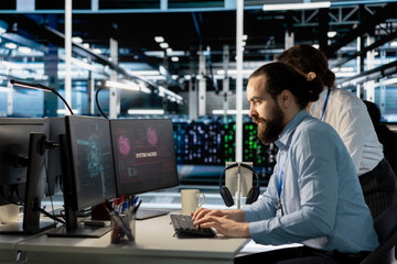 Engineers in data center reacting to ransomware alert on PC monitor, initiating protocol to protect...