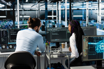 Obraz premium Manager and intern in server room using PC to review infrastructure diagnostics. IT specialist and trainee in data center analyzing performance data to maintain system uptime