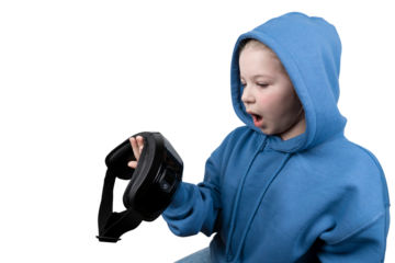 A curious young girl in a blue hooded sweatshirt with an open mouth, holding a black VR headset in her hand on a transparent background