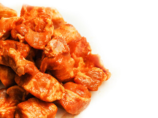 Close up of marinated pork belly bits on white background. Asian style food for cooking on a barbeque or oven. Ready to cook product. Red sweet chilly and honey marinade for pork belly slices.