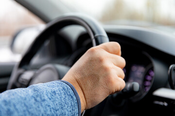 Close up man driver's hands on the steering wheel inside of a car while road trip. High quality photo