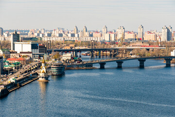 An aerial view of a vibrant city with a wide river spanned by a bridge, and a mix of historical and...
