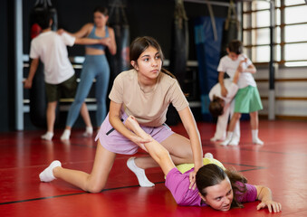 Teen girls paired in gym, perform basic elements of self-defense system. Preparation of athletes before competitions, physical activity, sports self-defense classes...