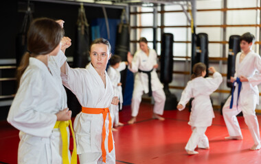 Teenage girls are actively engaged in judo. Children in white kimonos at a martial arts training...
