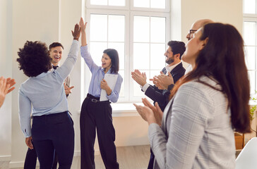 Team of positive business people gives each other high fives during a group meeting or conference...