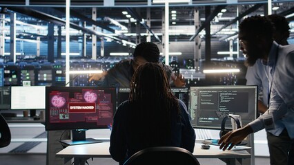 Cybersecurity team in data center responds to security breach, trying to prevent unauthorized access. Workers rushing to secure servers and protect sensitive information during cyberattack, camera A © DC Studio