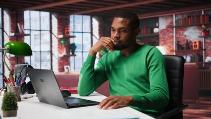 Teleworker fixing his back posture and suffering a muscle cramp at home desk, feeling fatigued and...