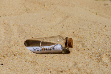Message in a bottle with coordinates lying on the sand