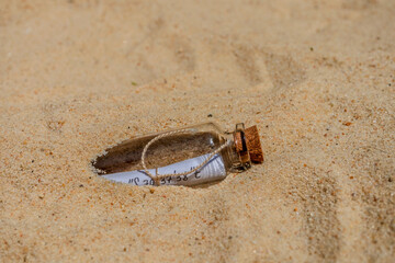 Message in a bottle emerging from beach sand