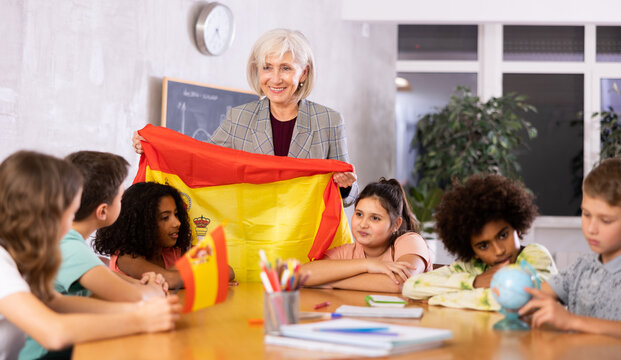 children listen with interest to the teacher, who talks about the geographical location Spain