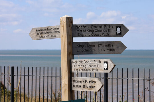 Wooden sign post on the Norfolk coastal Foot Path, near the beach, with sea and sky background