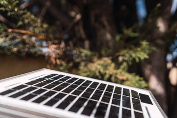Solar panel in sunlight against a blue sky and clouds on a sunny day with a background of trees,...