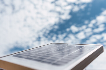 Solar panel in sunlight against a blue sky and clouds on a sunny day with a background of trees,...